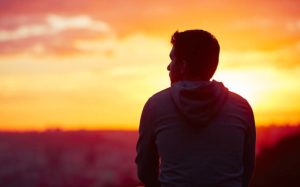 Young man is looking at the sunrise.